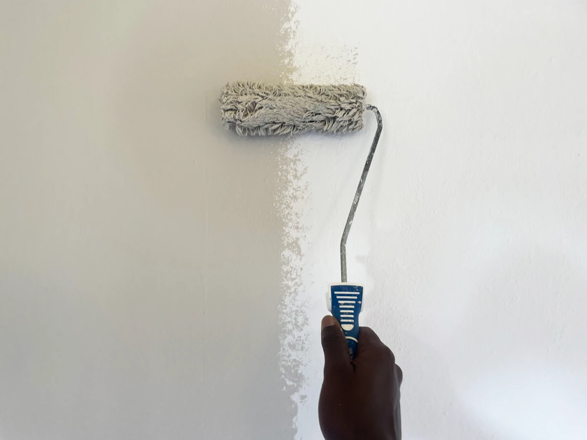 Rodillo pintando una pared de blanco