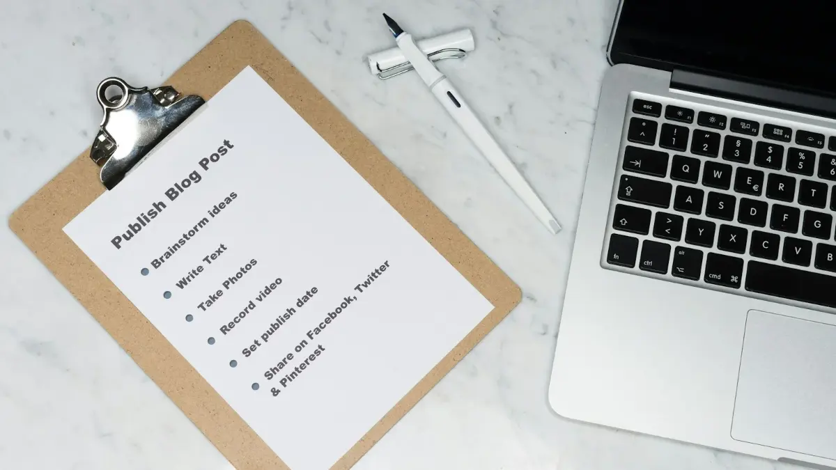 Lista de tareas en un portapapeles junto a un portátil