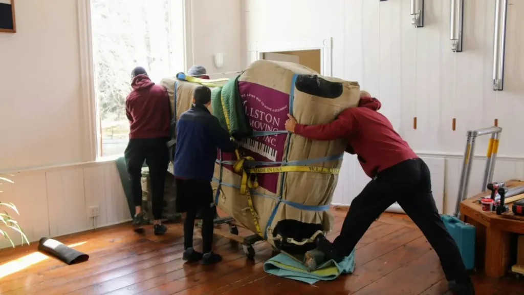 Personas cargando un mueble envuelto durante una mudanza